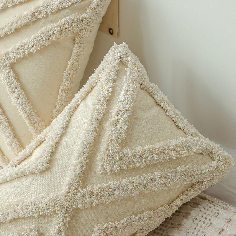 Coussin touffeté écru posé sur un canapé
